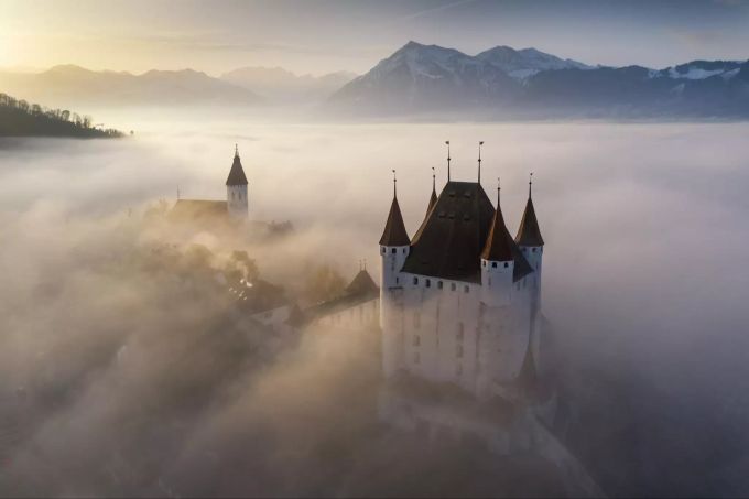 Blick vom Schloss Thun über den Thunersse in Richtung Alpen. Unverkennbares Erkennungszeichen sind die vier Türmchen und der zentrale Wehrturm, der sogenannte Donjon. s