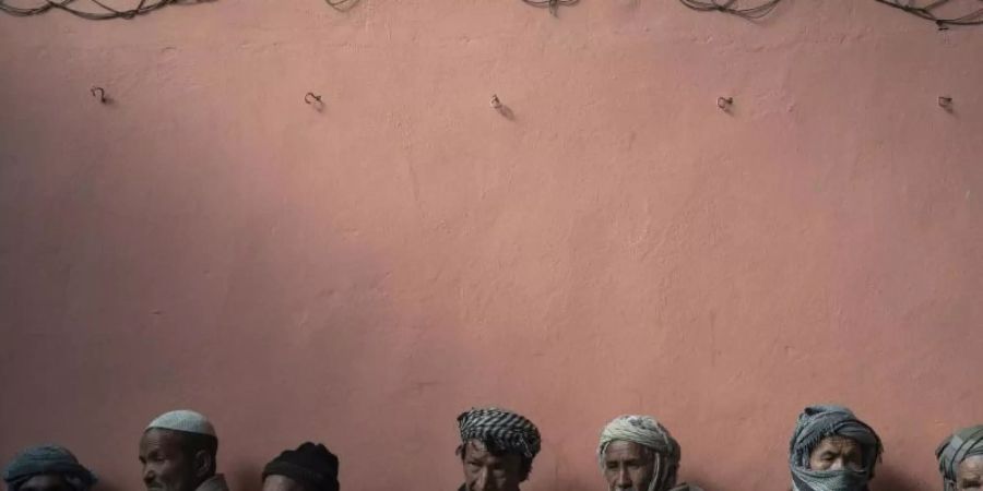 Männer warten in einer Schlange, um bei einer vom Welternährungsprogramm (WFP) organisierten Geldverteilung Bargeld zu erhalten. Foto: Bram Janssen/AP/dpa