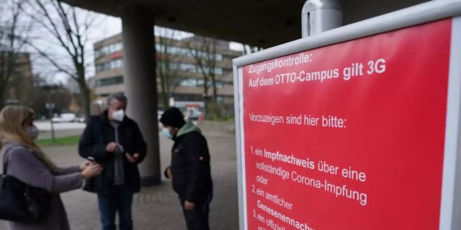 Mitarbeiter werden am Eingang des Otto-Campus der Otto Group gemäss den 3G-Regeln von Sicherheitsmitarbeitern kontrolliert. Foto: Marcus Brandt/dpa