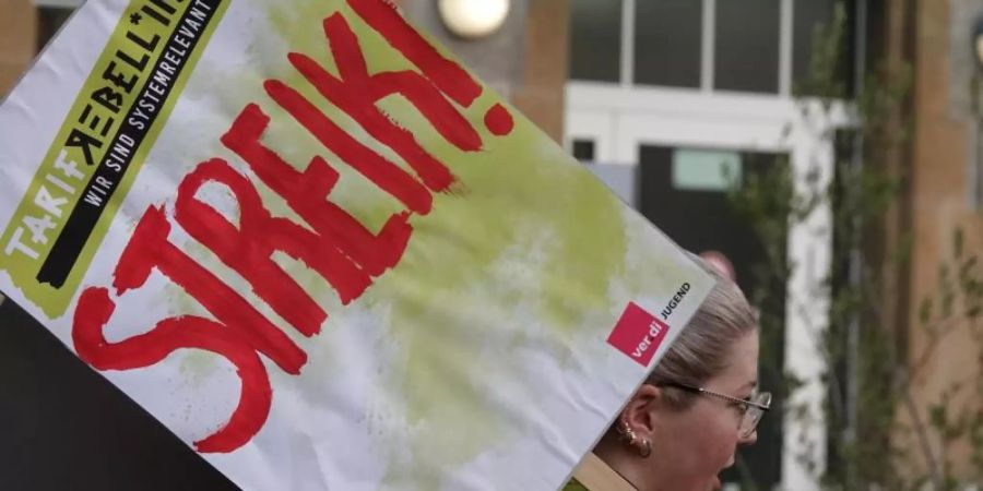 Eine Frau hält ein Schild hoch auf dem «Streik!» steht. Foto: Mona Wenisch/dpa