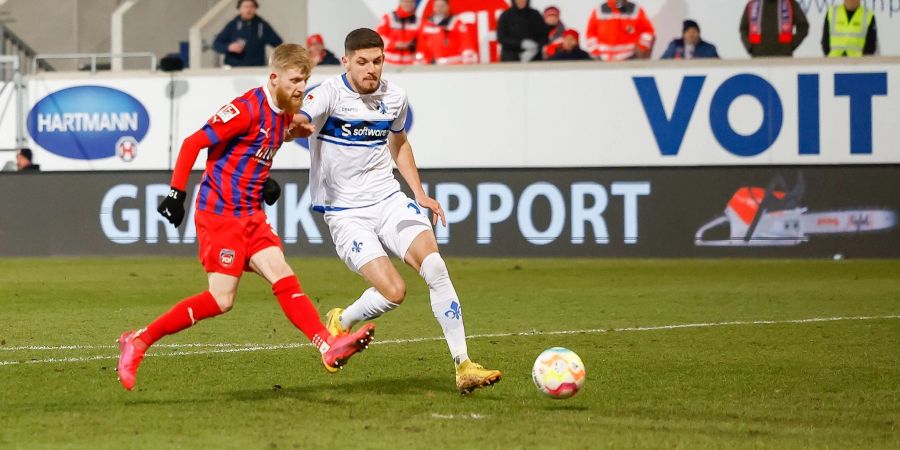 Der Heidenheimer Jan-Niklas Beste (l) schiesst das 1:0-Siegtor, der Darmstädter Emir Karic kann es nicht verhindern.