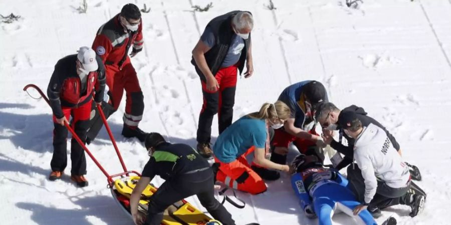 Sanitäter kümmern sich in Planica um den schwer gestürzten Daniel André Tande. Foto: Uncredited/AP/dpa