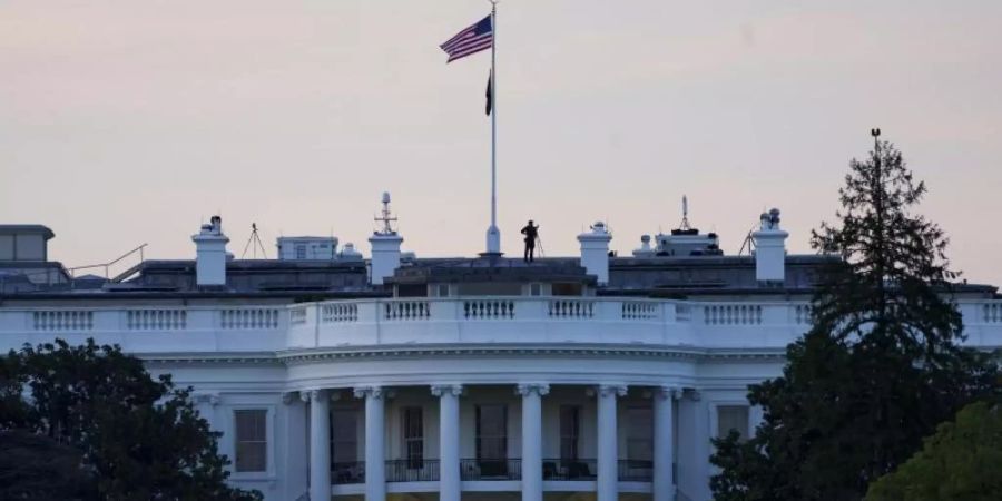 Die Flagge der USA weht bei Sonnenaufgang über dem Weissen Haus. Foto: Shen Ting/Xinhua/dpa
