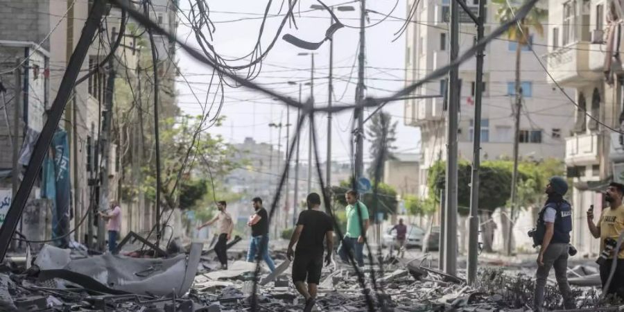 Palästinenser inspizieren das Umfeld des schwer beschädigten Al-Jawhara-Turm, nachdem der Turm von israelischen Luftangriffen getroffen worden war. Foto: Mohammed Talatene/dpa