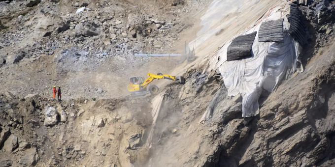 Arbeiter betrachten das Gestein nach der Sprengung von Felsen oberhalb eines Hauses im Steinbruch Raron. Raron