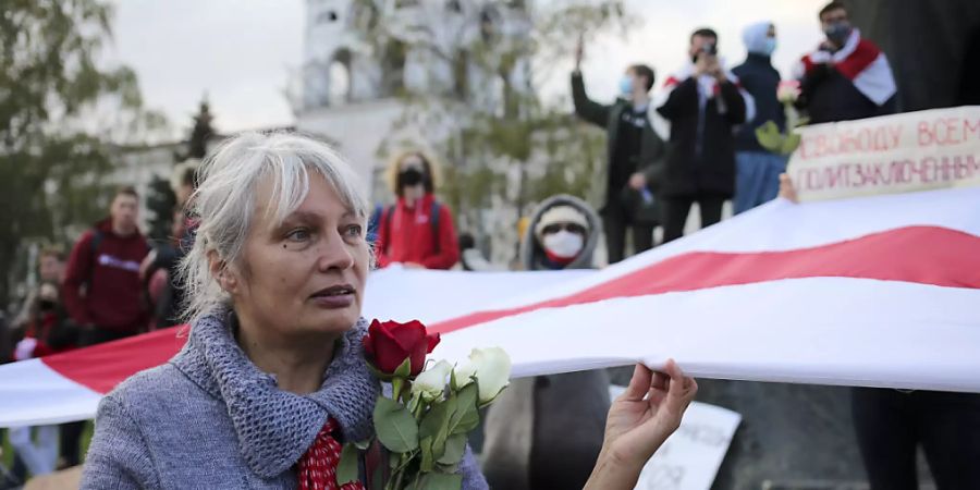 dpatopbilder - Eine Frau hält bei einer Demonstration Rosen und die historische weiss-rot-weisse Fahne in der Hand. Tausende Menschen, darunter vor allem Senioren und Studenten, marschierten am Montag durch die Hauptstadt. Foto: -/AP/dpa