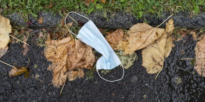 Eine benutzte Hygienemaske liegt weggeworfen auf dem Boden. Maske
