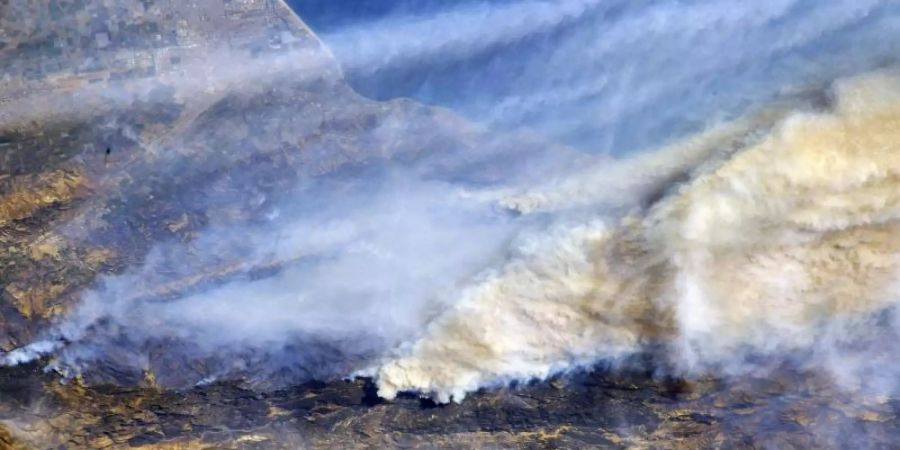 Riesige Rauchwolken sind von der Internationalen Raumstation (ISS) aus über Südkalifornien (USA) zu sehen. Die Waldbrände im Westen der USA sind aus Expertensicht auch eine Folge des Klimawandels. Foto: Randy Bresnik/Nasa/dpa