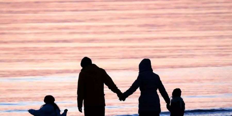 Eine Familie am Strand. Ein Grossteil der Adoptionen in Deutschland sind sogenannte Stiefkindadoptionen. Foto: Bernd Wüstneck/dpa-Zentralbild/dpa