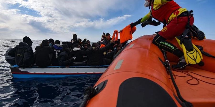 Mitglieder der NGO Open Arms helfen Migranten, die in einem Holzboot vor der Küste Libyens im Mittelmeer aufgebrochen sind. Foto: Antonio Sempere/EUROPA PRESS/dpa