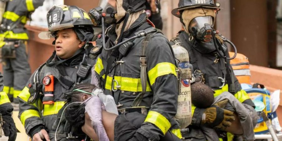 Feuerwehrleute tragen Kinder aus einem Wohnhaus in der Bronx. Bei dem Feuer sind nach Angaben des Bürgermeisters Adams 17 Menschen getötet worden. Foto: Theodore Parisienne/New York Daily News/TNS via ZUMA Press Wire/dpa