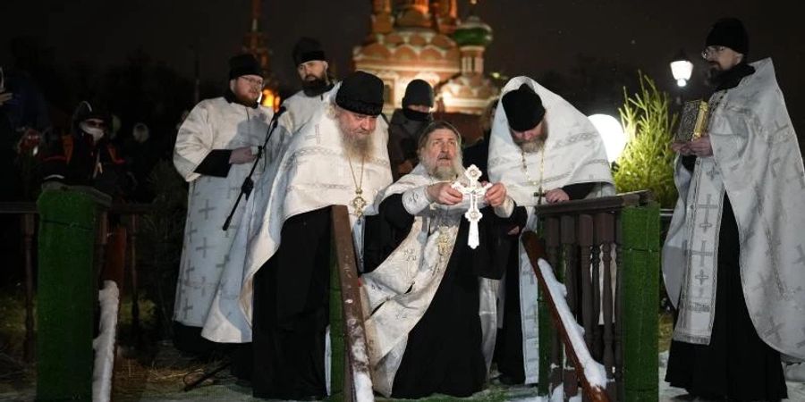 Ein russisch-orthodoxer Priester segnet am Dreikönigstag das eiskalte Wasser in der Kirche der Heiligen Dreifaltigkeit in Moskau. Foto: Alexander Zemlianichenko/AP/dpa