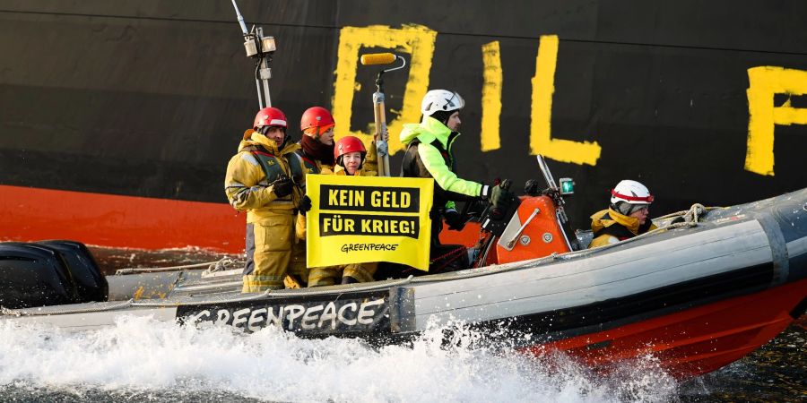 Aktivisten der Umweltorganisation Greenpeace malen den Schriftzug «Oil fuels war» auf den Rumpf eines Schiffes, das russisches Öl auf der Ostsee transportiert.