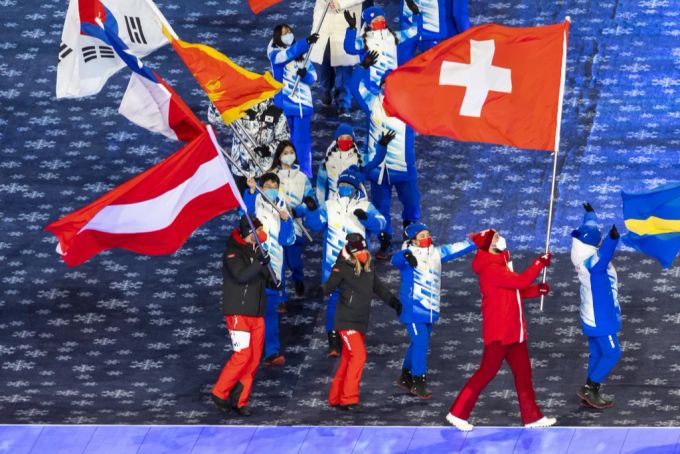 Ryan Regez marschiert mit der Schweizer Flagge ins Drachennest-Stadion. olympia 2022
