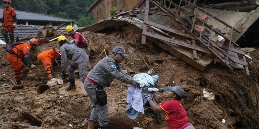 Rettungskräfte bergen am dritten Tag der Suche nach Überlebenden und Opfern der tödlichen Schlammlawinen in Petropolis Kleidung aus einem Haus. Foto: Silvia Izquierdo/AP/dpa