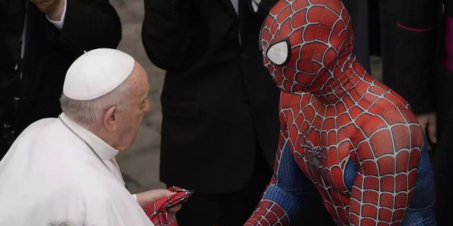 Papst Franziskus (l) spricht am Ende seiner wöchentlichen Generalaudienz mit einem Mann im Spiderman-Kostüm. Foto: Andrew Medichini/AP/dpa