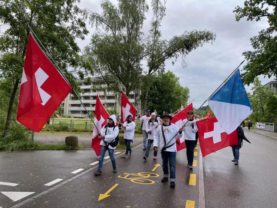In Uster zieht eine Menschenmenge mit Kuhglocken und Fahnen durch die Stadt.