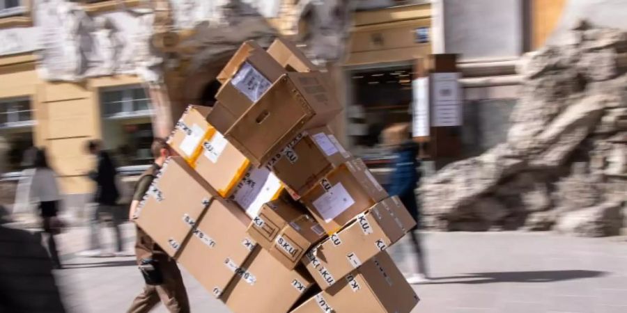 Ein Paketzulieferer transportiert mit einer Sackkarre mehrere Pakete durch die Münchener Innenstadt. Foto: Peter Kneffel/dpa