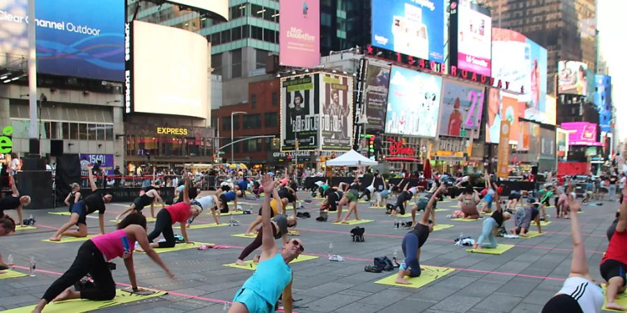 Menschen nehmen an einer gemeinsamen Yoga-Stunde inmitten des Times Square teil. Foto: Christina Horsten/dpa