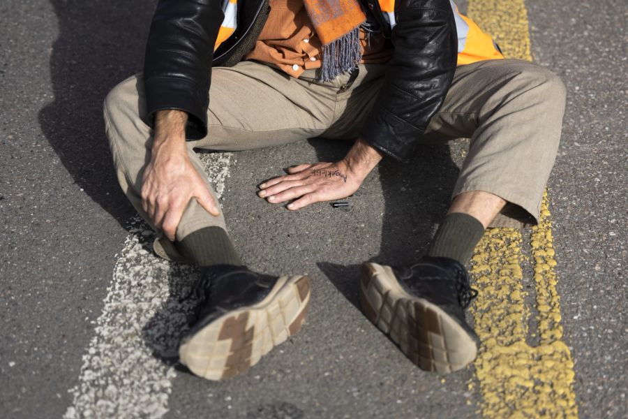 Einige Aktivisten kleben bei den Aktionen sogar ihre Hände auf den Asphalt. (KEYSTONE/Peter Klaunzer)