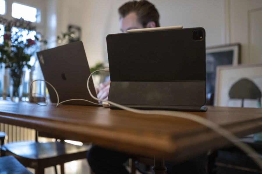 Ein Mann arbeitet mit einem Laptop und einem Tablet am Esstisch im Homeoffice, fotografiert am Mittwoch, 5. Januar 2022 in Zürich.