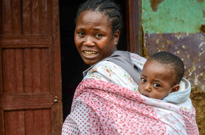 Demekeen, 25, aus Äthiopien lernt in einem speziellen World Vision-Programm für Mütter Karotten, Randen, Spinat, Zwiebeln, Mais und Erbsen anzubauen. Schwarze Frau mit Kind