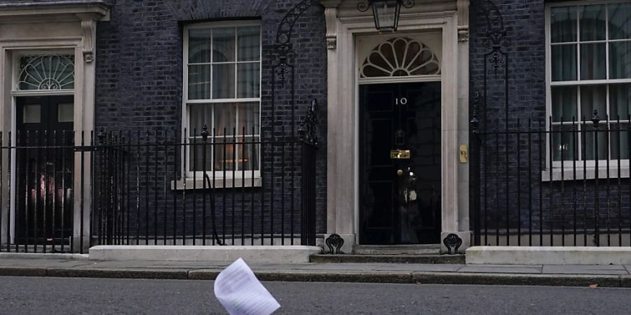 ARCHIV - Eine Kopie des Berichts zu den mutmasslichen Lockdown-Verstössen im britischen Regierungssitz fliegt an der Eingangstür der 10 Downing Street vorbei. Foto: Alberto Pezzali/AP/dpa