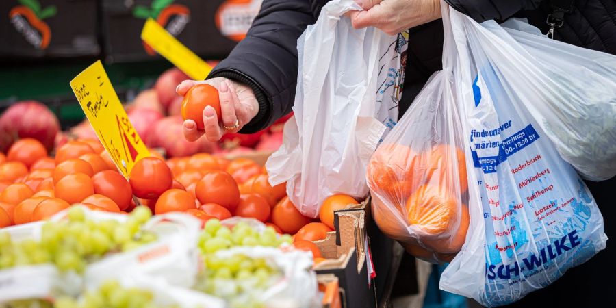 Eine Kundin begutachtet eine Tomate auf einem Wochenmarkt in Hannover. Wegen der steigenden Inflation müssen viele Menschen in Deutschland den Gürtel enger schnallen,