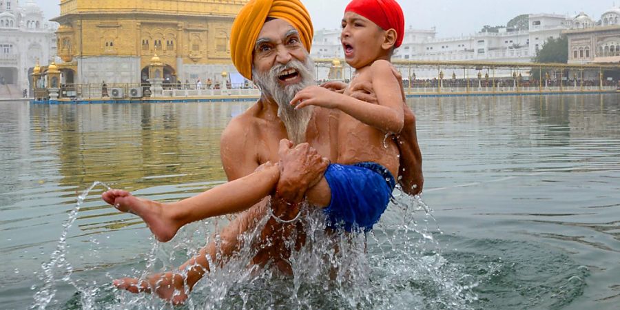 dpatopbilder - Ein Sikh-Gläubiger nimmt mit einem Familienmitglied ein heiliges Bad im «Sarovar» während des Makar-Sankranti-Festes. Foto: Shiva Sharma/PTI/dpa