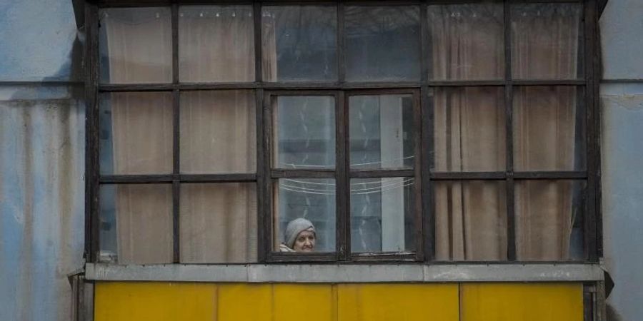 Eine Frau blickt aus dem Fenster eines Hauses in Sjewjerodonezk im Osten der Ukraine.