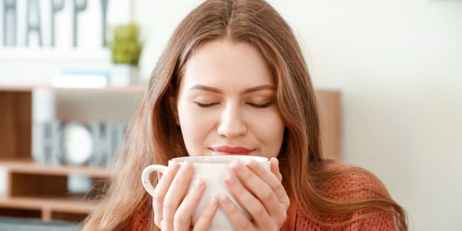 Frau geniesst bewusst ihre Tasse Tee.