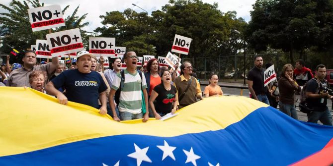 Demonstranten halten die Flagge Venezuelas und Schilder.