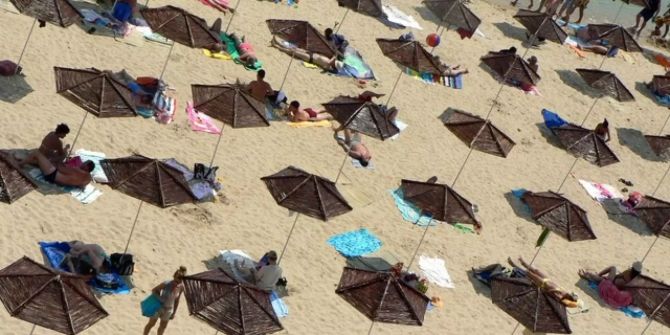 Urlauber sonnen sich auf einem Strand.