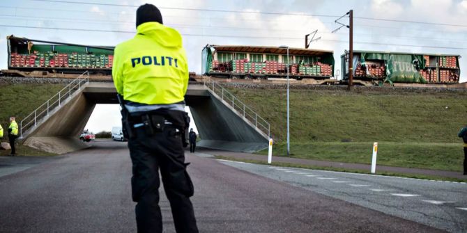 Ein Polizist steht vor dem verwüsteten Zug.