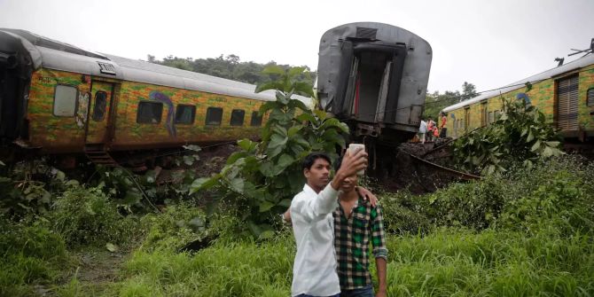 Zwei indische Jungen machen ein Selfie vor dem Bahngleis, auf dem es z