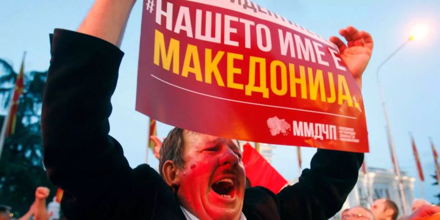 Ein Mann hält an der Demonstration ein Schild hoch. Darauf steht geschrieben: «Unser Name ist Mazedonien».