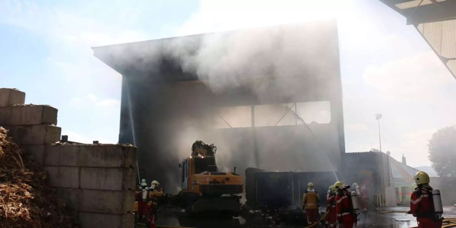 Feuerwehrleute bekämpfen den Brand in einer Halle für Sperrgut in Neftenbach ZH.