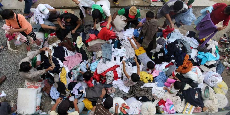 Menschen, die wegen Taifun «Mangkhut» ihr zu Hause verloren haben, erhalten hier in einer temporären Unterkunft Kleidung.