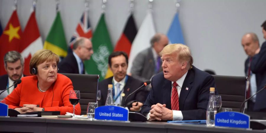 Bundeskanzlerin Angela Merkel (l, CDU) und Donald Trump, Präsident von USA, nehmen an der Arbeitssitzung am zweiten Tag des G20-Gipfels teil.