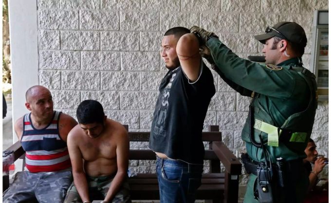 Ein US-Grenzpolizist legt einem Mann aus Mexiko Handschellen an, der verdächtigt wird, illegal die Grenze zu den USA überquert zu haben. Donald Trump Grenzpolizist Mexiko