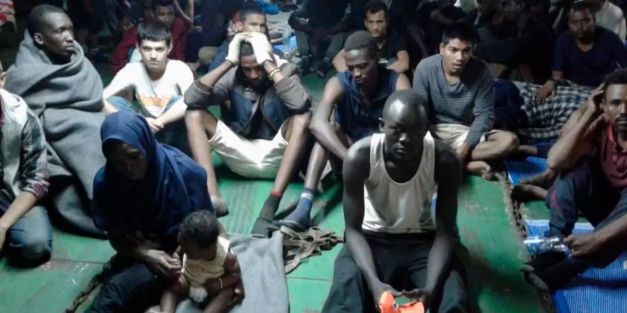 Migranten sitzen vor Libyen an Bord eines Containerschiffes.