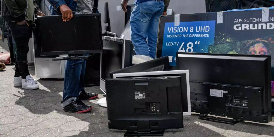 Passanten durchsuchen Elektroschrott auf dem Fussweg in Hamburg (D)