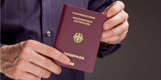 Ein Mann hält einen deutschen Reisepass. Ein Mann hält einen deutschen Reisepass.