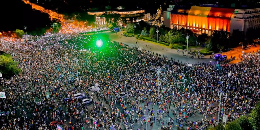 Rumänien, Bukarest: Menschen versammeln sich am zweiten Tag ihrer Proteste vor dem Regierungssitz und leuchten mit Laserlicht und Taschenlampen.