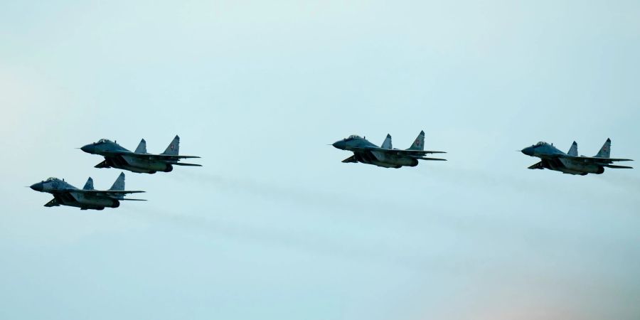 Kampfjets vom Typ MiG-29 fliegen während einer Flugshow in der Slowakei über einen Flughafen.