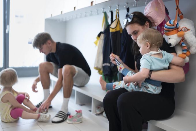 Ein Betreuer und eine Betreuerin bereiten zwei Kinder auf das Spielen im Freien vor. (Symbolbild) Kita