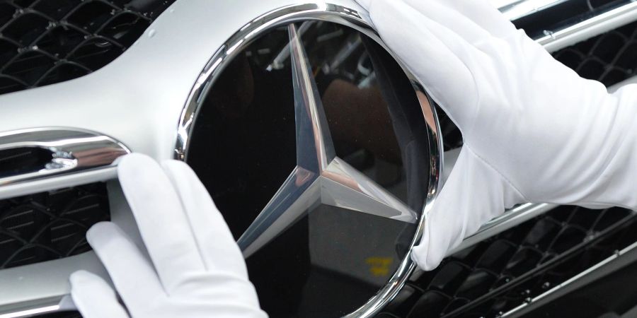 Ein Mitarbeiter von Mercedes-Benz bringt im Werk in Bremen den Stern an einem C-Klasse Modell an.
