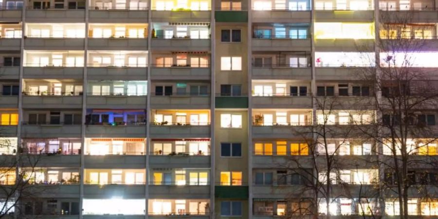 In einem Hochhaus sind einige Fenster beleuchtet. Foto: Christophe Gateau/dpa