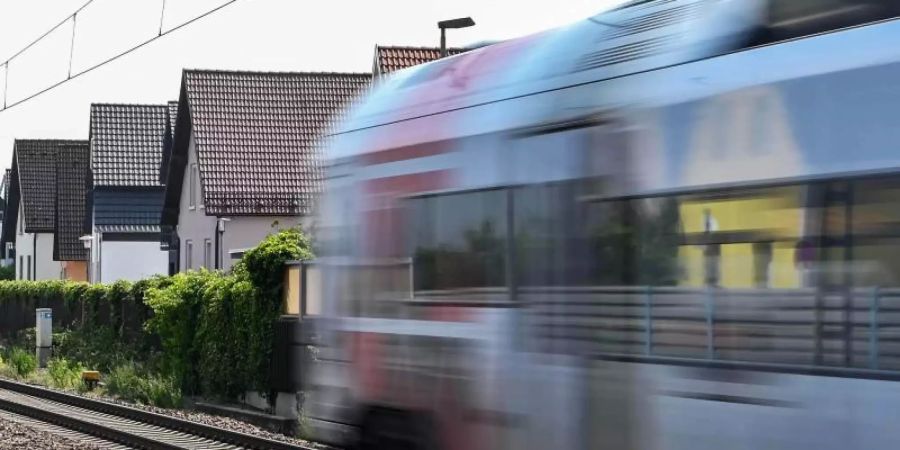 Auf der Bahnstrecke Karlsruhe-Mannheim fährt ein Zug an Häusern vorbei. Foto: Uli Deck/dpa