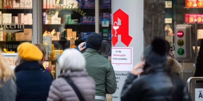Passanten stehen Schlange vor einer Apotheke. vitamin d
